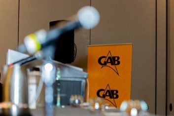 Photo of the GAB logo on a banner behind a microphone