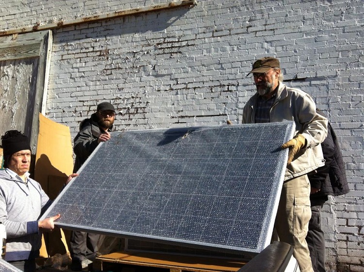 Volunteers prepare to install solar panels on the roof of the KUHS studio building.