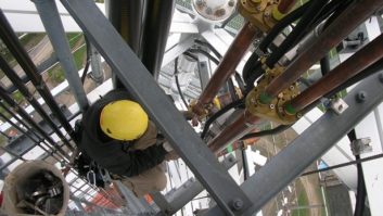 Photo of crew installing coaxial cable hangers on a tower