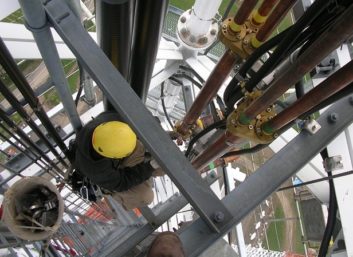 Photo of crew installing coaxial cable hangers on a tower