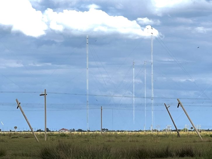 An image of the WRMI tower farm with damaged phone poles in the foreground. The poles carry transmission lines.