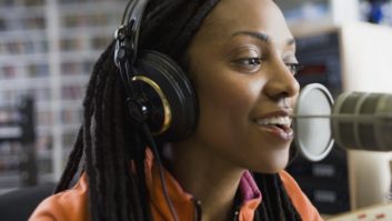 A young African-American woman talking into a microphone in a radio studio