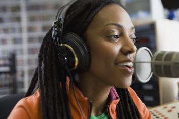 A young African-American woman talking into a microphone in a radio studio