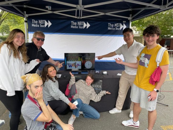 Students from WRHU visit a booth at the Next Best Thing Media Tour and point to a Sprite Media Broadcast Clock in the exhibit