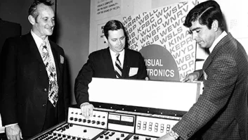 Archival photo from the floor of the 1971 NAB Show with three men looking at an audio console in an exhibit booth