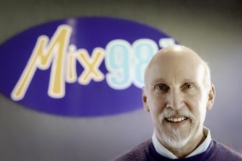 John Anthony standing in front of the Mix 98.7 logo