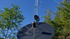 Photo of the tower, wind turbine and satellite dish serving the FM translator for KCAW in Sitka, Alaska