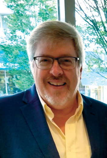 Dale Ladner standing in front of a window overlooking foliage