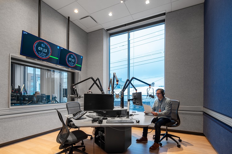 KQED Radio Studio B, with a central table equipped with mic arms and a large window to the outside