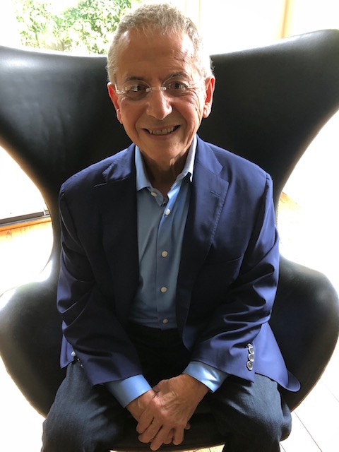 Rick Cummings sitting in a modernistic chair and wearing a blue blazer