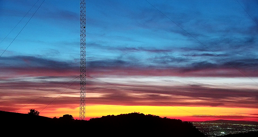 Sunset view of the KBRT Oak Flat transmitter site in the Santa Ana Mountains, looking down on a populous part of eastern Orange County, Calif. Part of a radio tower is at left, near the viewer.