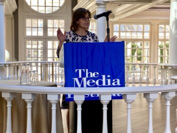 Commissioner Anna Gomez speaking at a podium at the Media Institute
