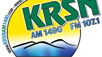 Logo of the former KRSN with the call letters in green over a cartoon image of mountains and sunshine