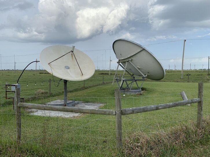 Satellite dishes within a fenced area.