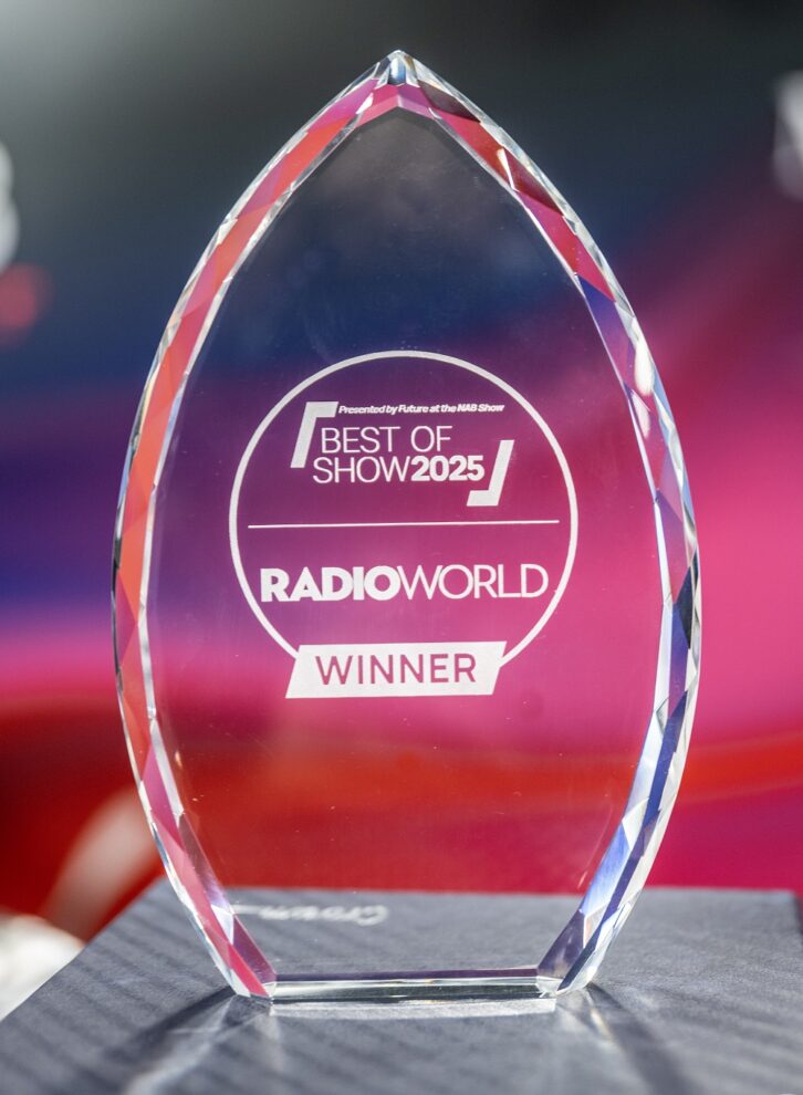 A crystal glass trophy sits in front of a reddish background. The trophy lettering reads "Best of Show 2025 Radio World Winner"