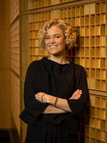 Photo of a woman leaning against acoustic paneling in a radio studio