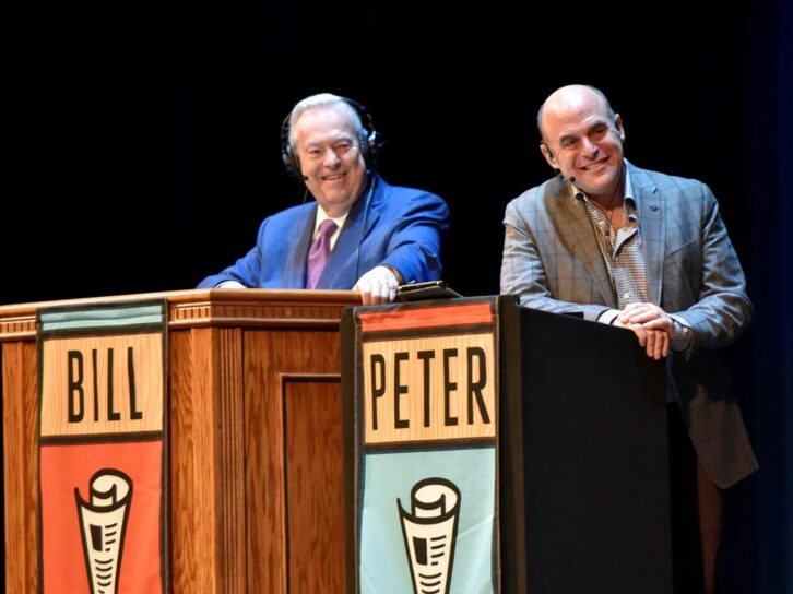Bill Kurtis and Peter Sagal are shown on the road.