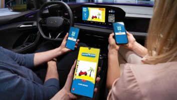 A view from the backseat of a parked car, showing the hands of the driver and two passengers playing video games on their phones, connected to the infotainment screen on the dashboard