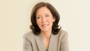 A woman wearing a business blazer smiles at the camera.