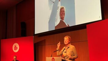 Jacqueline Bierhorst speaking at IBC2024, with a photo of her visit to the top of the broadcast tower in the south of Amsterdam.