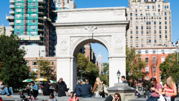 "New York City, United States - October 11, 2012: Students and tourists relaxing in the sun at Washington Square Park in Greenwich Village. Popular meeting place in manhattan and center of the cultural activity in the heart of New York University."
