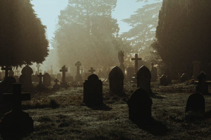 A spooky Victorian graveyard. With graves silhouetted by fog on a mysterious creepy winters night.