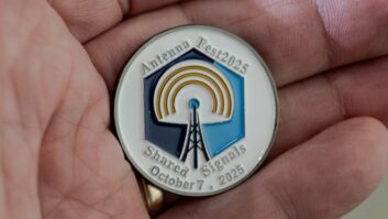 A medallion in the palm of a hand, with the logo of the AntennaFest event on it