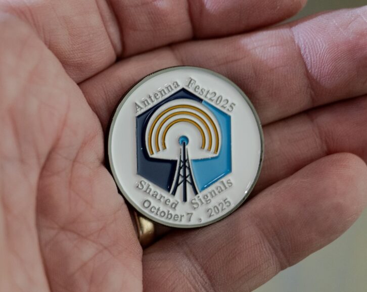 A medallion in the palm of a hand, with the logo of the AntennaFest event on it
