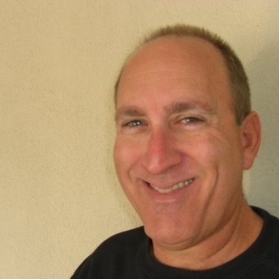 A man wearing a black T-shirt smiles at the camera