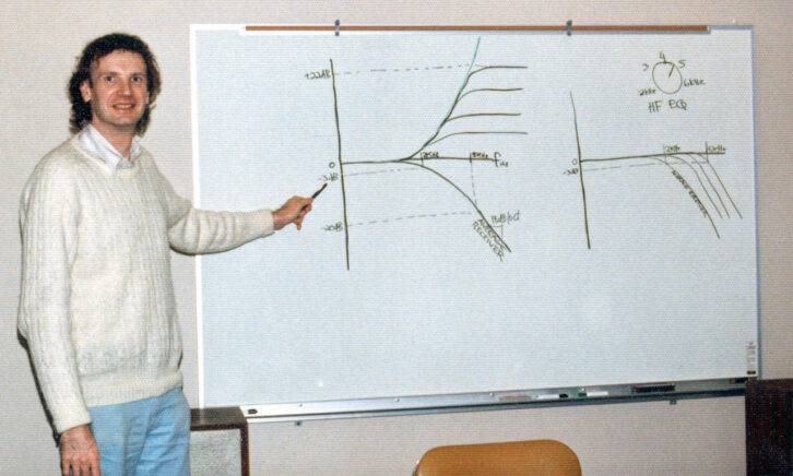 A man stands in front of a white board that displays a technical diagram.