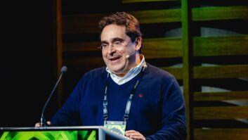 A man stands at a podium wearing a headset mic