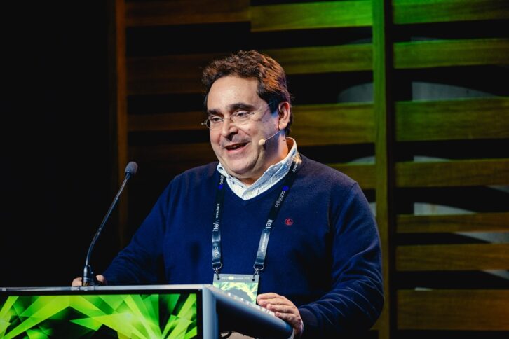 A man stands at a podium wearing a headset mic