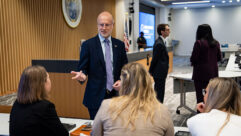 Brendan Carr stands in a conference room speaking to members of the FCC staff.
