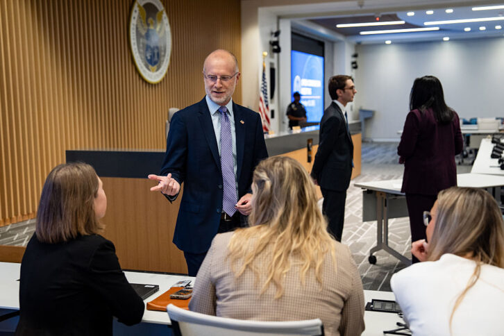 Brendan Carr stands in a conference room speaking to members of the FCC staff.