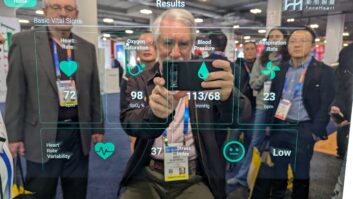 John Garziglia, with New Jersey radio broadcaster group owner Bob McAllan of Press Communications LLC to the left, reflected in the CardioMirror at CES 2025 taking a photo of his instantly rendered health measurements.