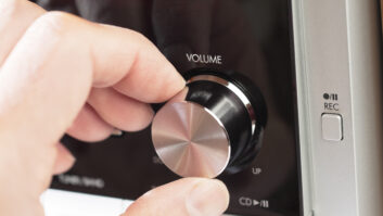 Man's hand turning the volume knob on a hi fi