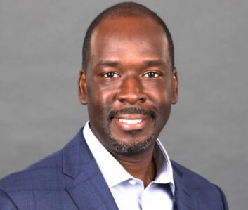 LaFontaine Oliver headshot. He wears a light blue sports jacket and open-necked business shirt