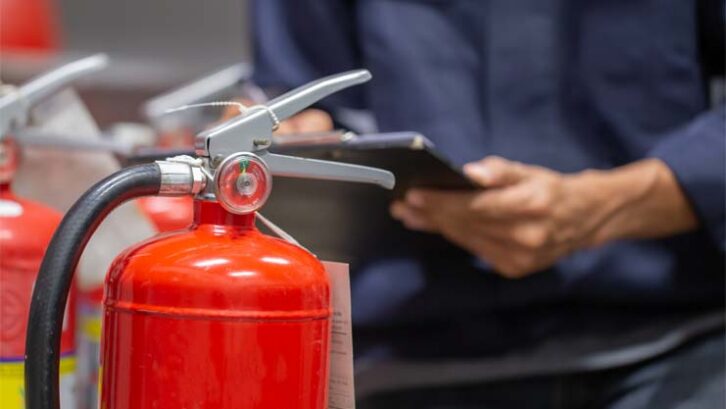 An engineer checks a fire extinguisher.
