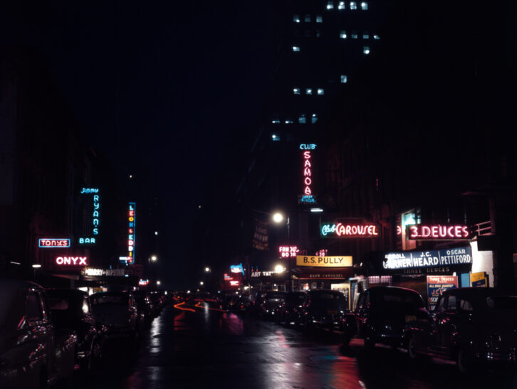 Swing Alley, 52nd Street between Fifth and Sixth Avenues, was once home to many jazz clubs and restaurants. Except for the shuttered “21” club and its outside lawn jockeys, the block is now dominated by glass and steel skyscrapers. (Photo via Wikipedia)