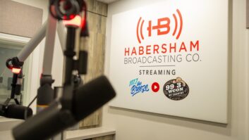 A sign with the logos of Habersham Broadcasting hangs on the inside wall of a radio studio