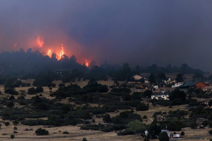 The Aspen Acres fire burns behind homes on July 3, 2026 in Rye, Colo.