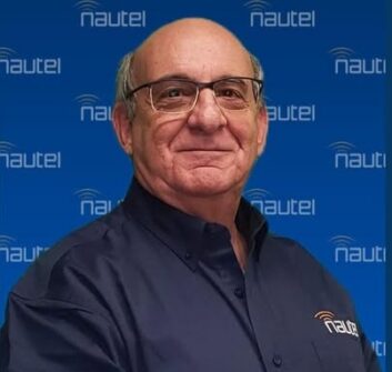 Ted Nahil stands in front of a background of Nautel logos