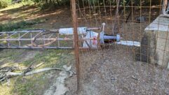 A close-up view of the WLNC tower base, base insulator, and feedline connection after the guy wire tension failure pulled the entire structure off its pier.