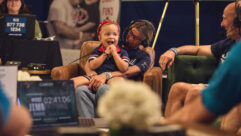 A Dana-Farber pediatric patient smiles on-air alongside loved ones during a live interview segment at Fenway Park.