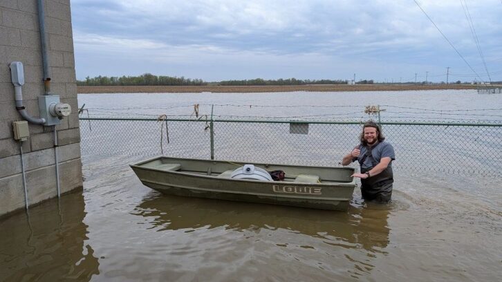 Giving a thumbs-up while wading through floodwaters to transport recovery equipment by boat.