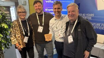 Four people in the On Air Solutions booth at IBC with an award