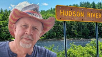 Promotional image of Uncle Mike Hansen wearing a cowboy hat and standing in front of a Hudson Valley road sign