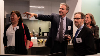 Joel Oxley, right, shows guests around WTOP’s new facilities in 2019. Walking behind him are Stanley Hubbard and Karen Hubbard. At work, seated center, is Zeke Hartner, and at lower right Jack Pointer. The station was also celebrating 50 years as an all-news outlet.