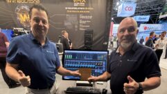 Two men stand in the Wheatstone booth at IBC 2026 with a computer screen and an award