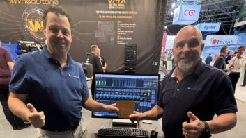 Two men stand in the Wheatstone booth at IBC 2026 with a computer screen and an award